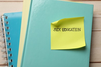 Photo of Sticky note with words Sex Education and notebooks on wooden table, top view