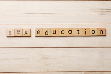 Photo of Words Sex Education made of squares on wooden table, flat lay