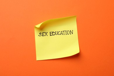 Photo of Sticky note with words Sex Education on orange background, top view