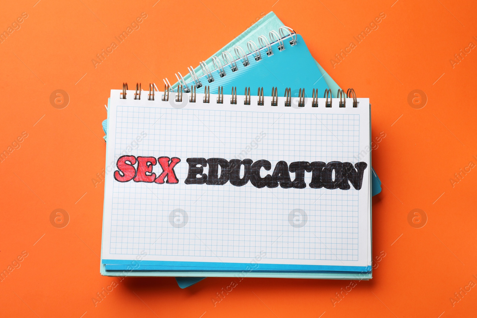 Photo of Notebook with words Sex Education and other stationery on orange background, top view