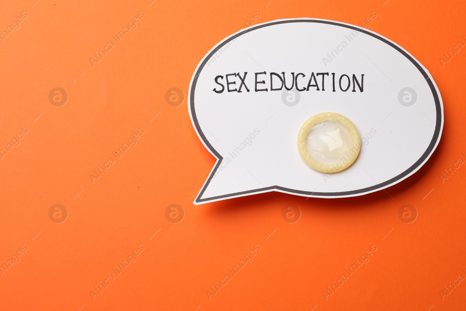 Photo of Paper speech bubble with words Sex Education and condom on orange background, top view. Space for text