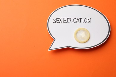 Photo of Paper speech bubble with words Sex Education and condom on orange background, top view. Space for text