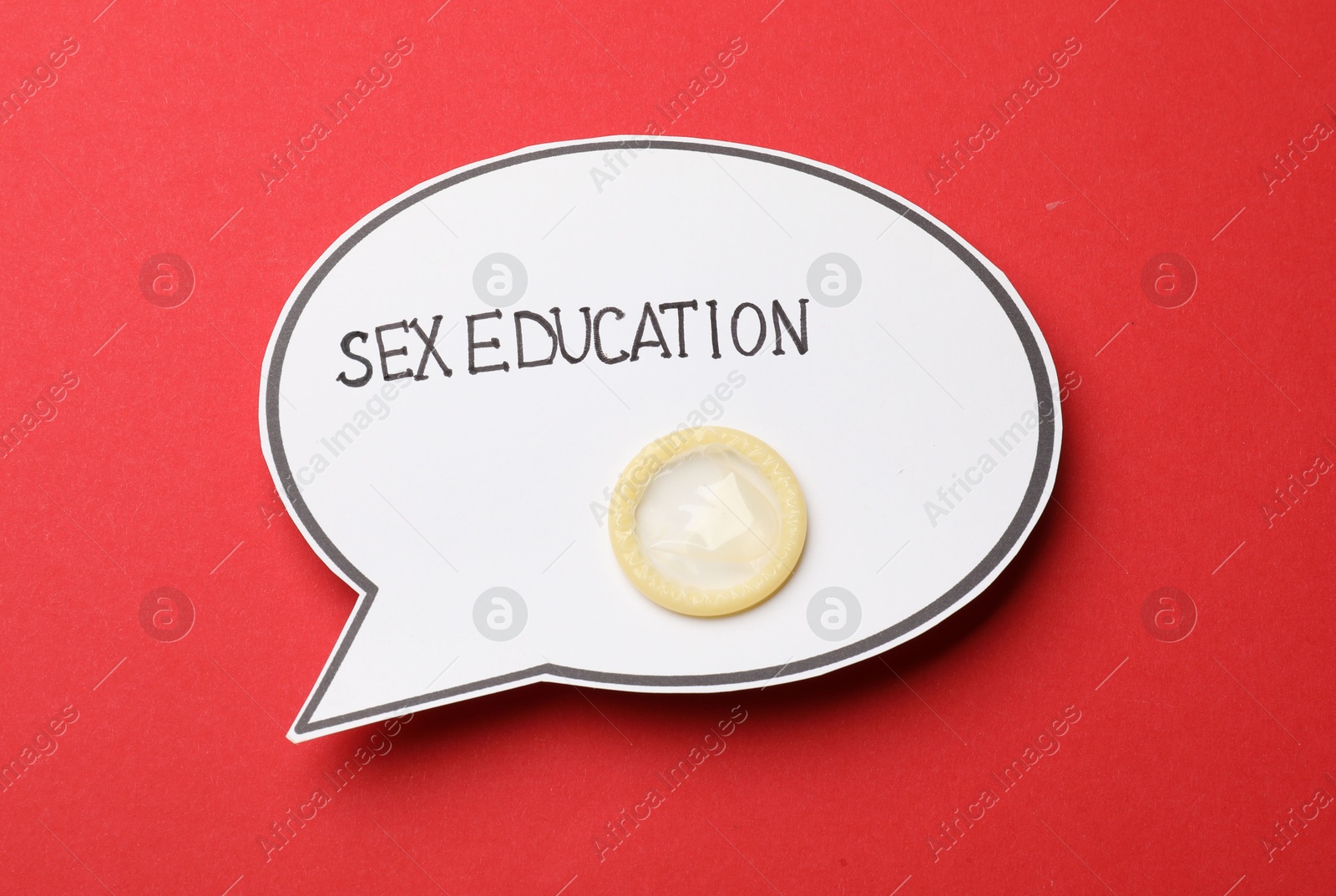 Photo of Paper speech bubble with words Sex Education and condom on red background, top view