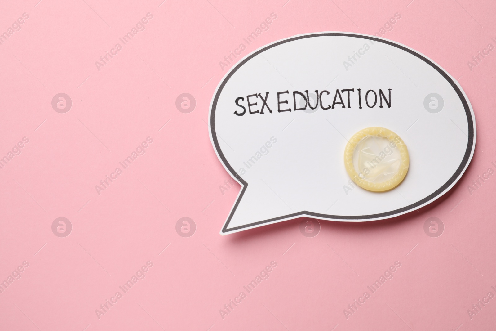 Photo of Paper speech bubble with words Sex Education and condom on pink background, top view. Space for text