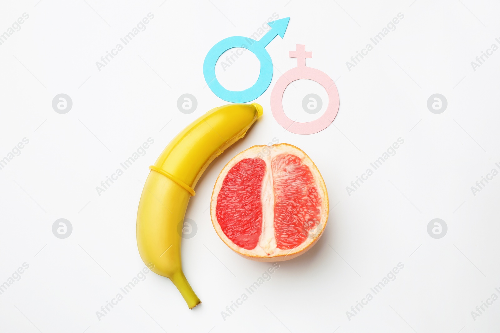 Sex education. Banana with condom, grapefruit, paper female and male gender symbols on white background, flat lay Photo of Sex education. Banana with condom, grapefruit, paper female and male gender symbols on white background, flat lay