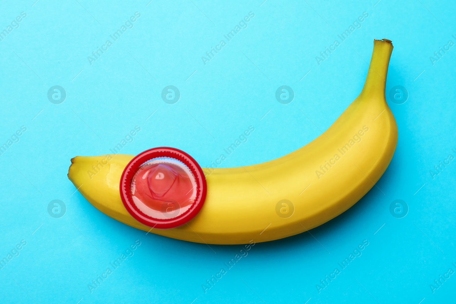 Sex education. Banana with condom on light blue background, top view Photo of Sex education. Banana with condom on light blue background, top view