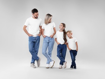 Photo of Happy parents and their children posing on grey background. Family