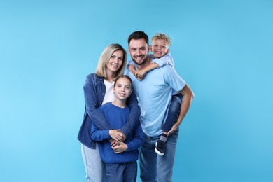 Photo of Family portrait of happy parents and their children on light blue background
