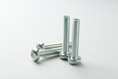 Photo of Many metal bolts on light grey background, closeup. Hardware tool