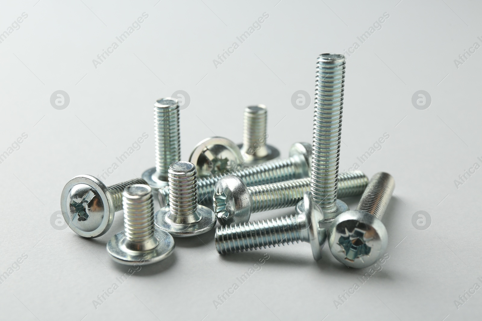 Photo of Many different metal bolts on light grey background, closeup. Hardware tool