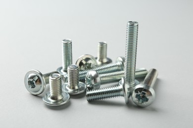 Photo of Many different metal bolts on light grey background, closeup. Hardware tool