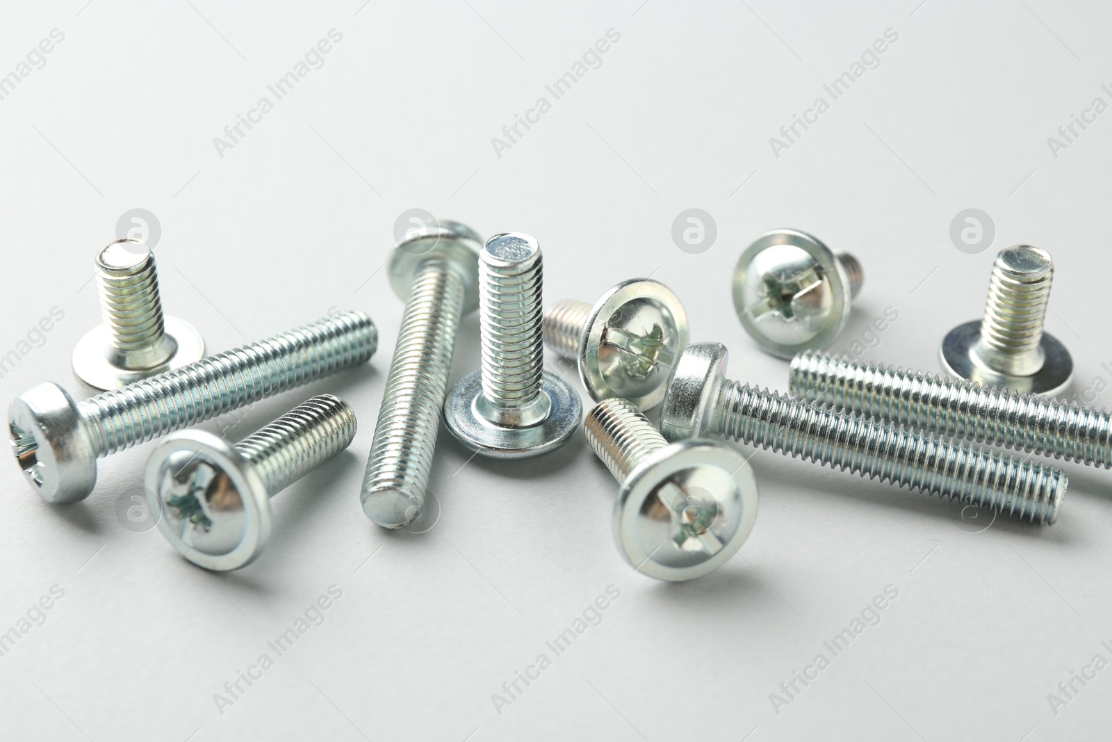 Photo of Many different metal bolts on light grey background, closeup. Hardware tool