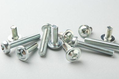 Photo of Many different metal bolts on light grey background, closeup. Hardware tool