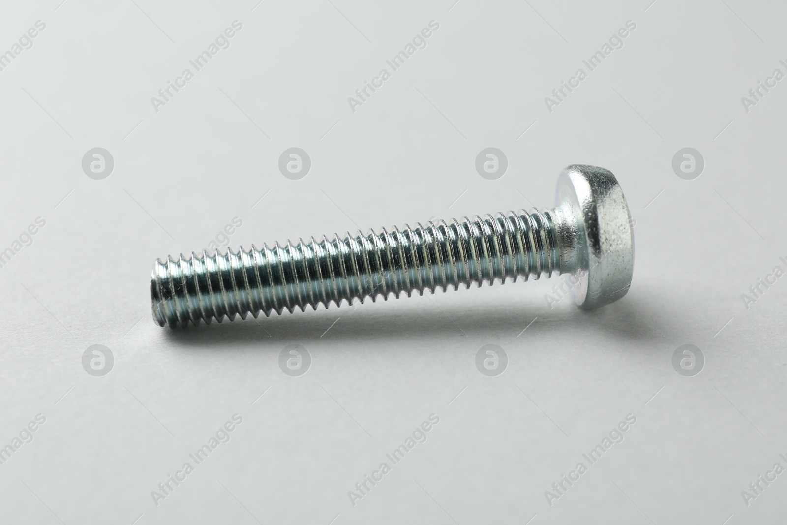 One metal bolt on light grey background, closeup. Hardware tool Photo of One metal bolt on light grey background, closeup. Hardware tool