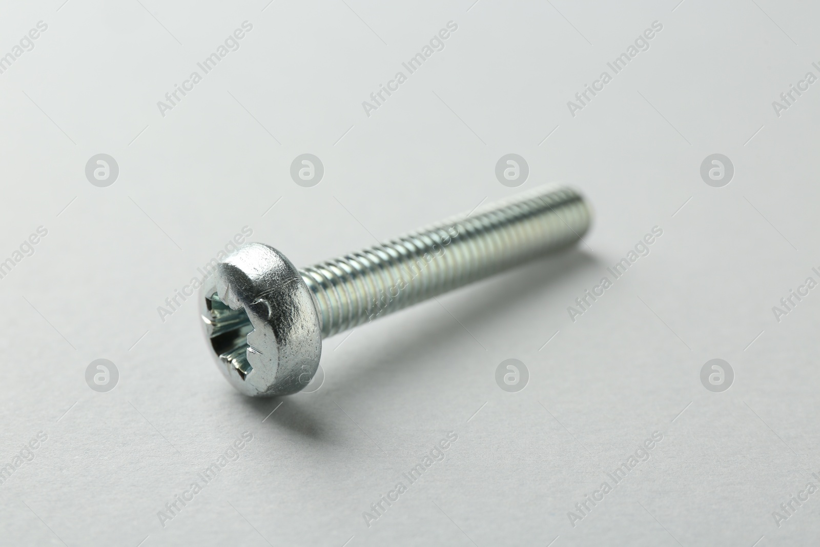 One metal bolt on light grey background, closeup. Hardware tool Photo of One metal bolt on light grey background, closeup. Hardware tool