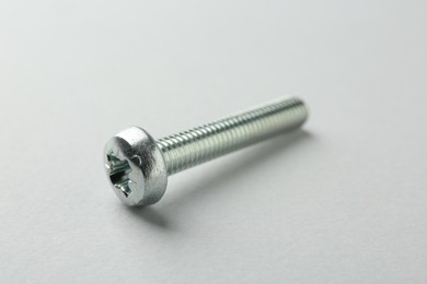 Photo of One metal bolt on light grey background, closeup. Hardware tool