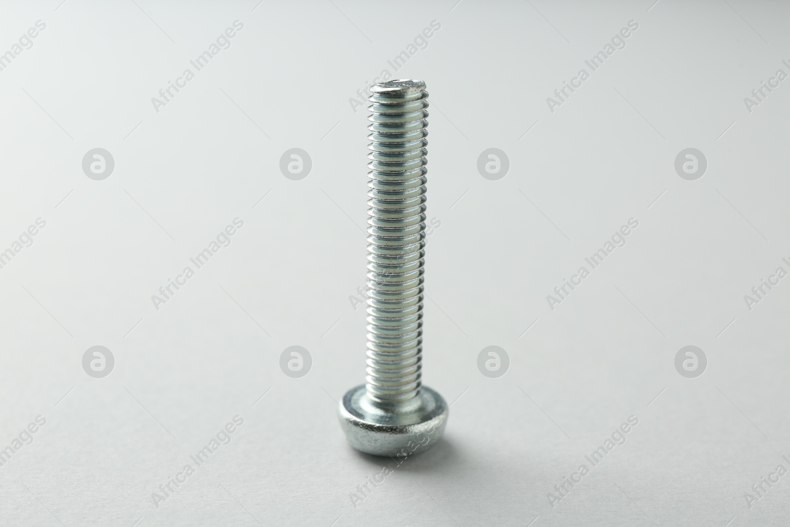 One metal bolt on light grey background, closeup. Hardware tool Photo of One metal bolt on light grey background, closeup. Hardware tool