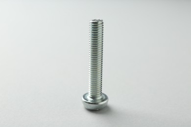 Photo of One metal bolt on light grey background, closeup. Hardware tool