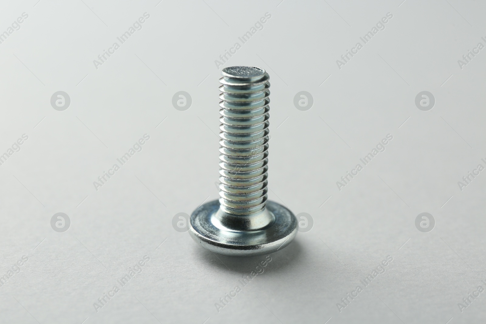One metal bolt on light grey background, closeup. Hardware tool Photo of One metal bolt on light grey background, closeup. Hardware tool