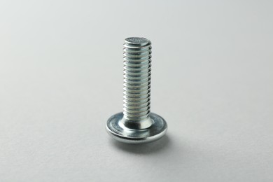 Photo of One metal bolt on light grey background, closeup. Hardware tool