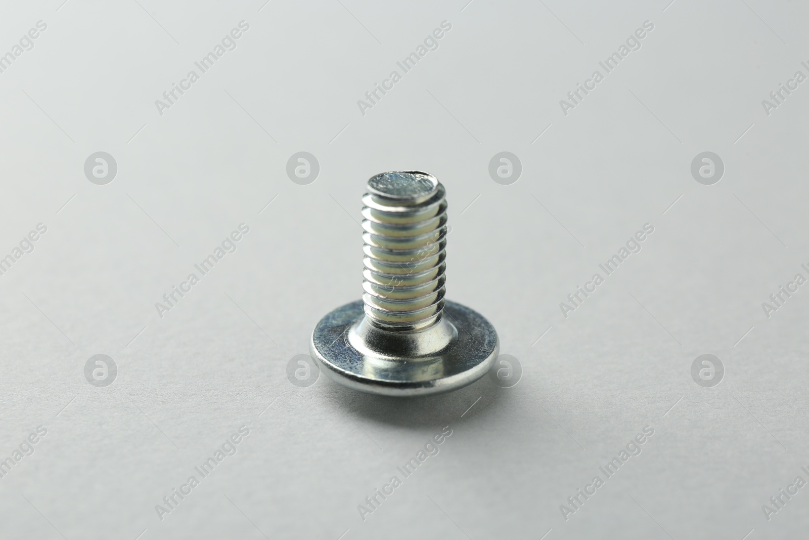 One metal bolt on light grey background, closeup. Hardware tool Photo of One metal bolt on light grey background, closeup. Hardware tool