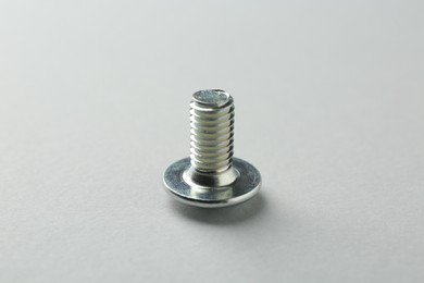 Photo of One metal bolt on light grey background, closeup. Hardware tool