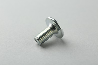 Photo of One metal bolt on light grey background, closeup. Hardware tool