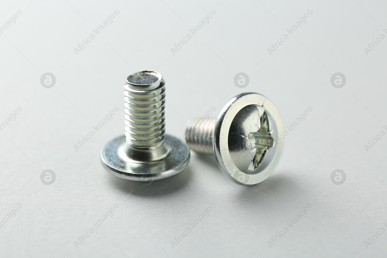 Photo of Two metal bolts on light grey background, closeup. Hardware tool