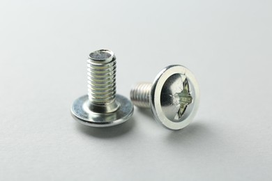 Photo of Two metal bolts on light grey background, closeup. Hardware tool