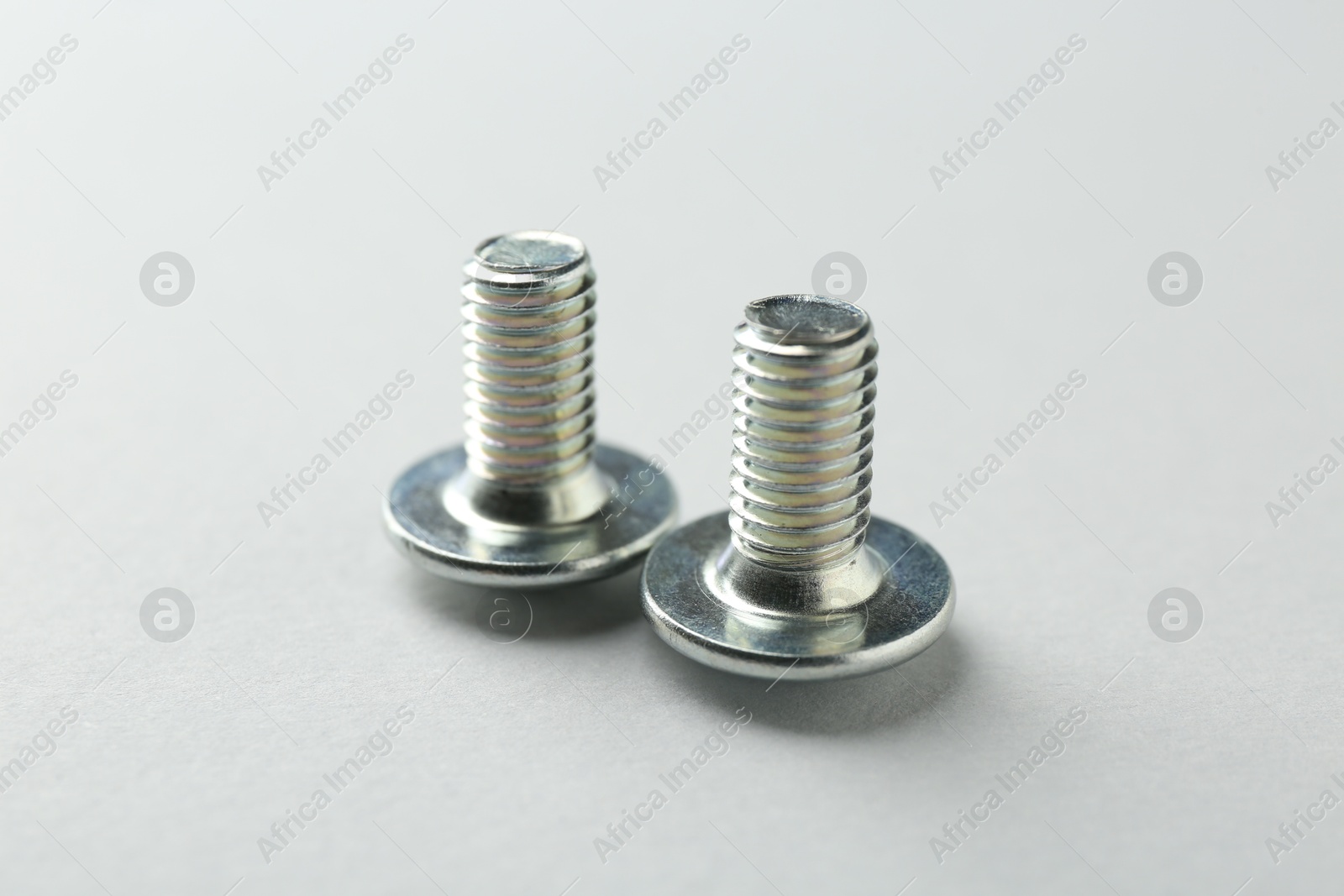 Two metal bolts on light grey background, closeup. Hardware tool Photo of Two metal bolts on light grey background, closeup. Hardware tool