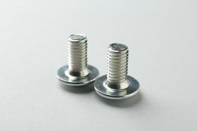 Photo of Two metal bolts on light grey background, closeup. Hardware tool