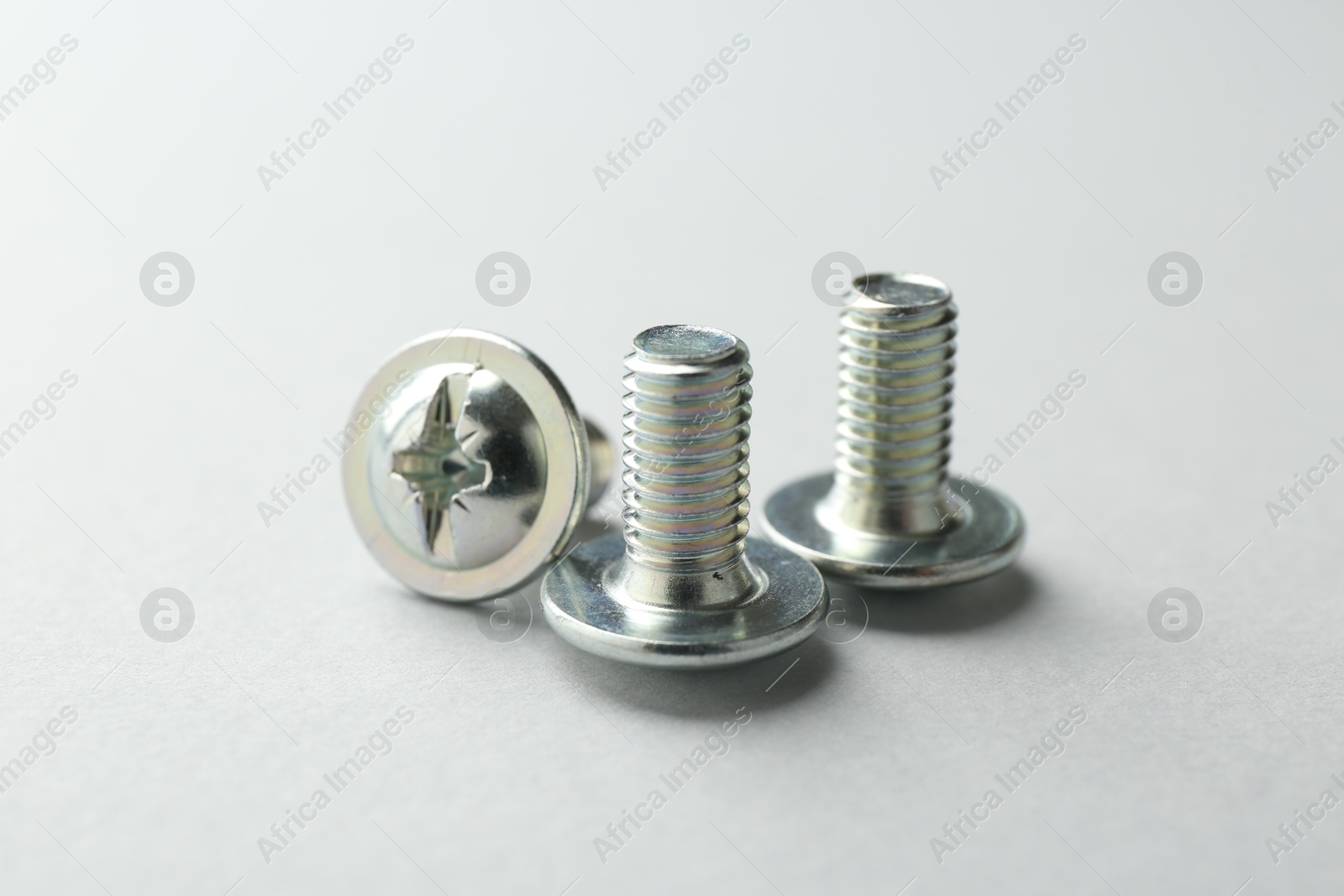 Three metal bolts on light grey background, closeup. Hardware tool Photo of Three metal bolts on light grey background, closeup. Hardware tool