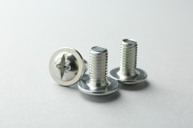 Photo of Three metal bolts on light grey background, closeup. Hardware tool