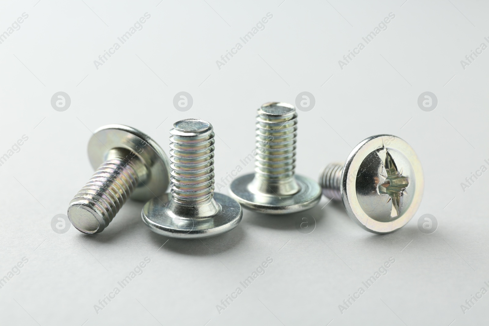 Photo of Many different metal bolts on light grey background, closeup. Hardware tool