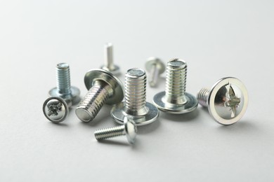 Photo of Many different metal bolts on light grey background, closeup. Hardware tool
