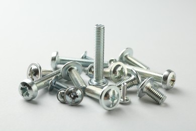 Photo of Many different metal bolts on light grey background, closeup. Hardware tool