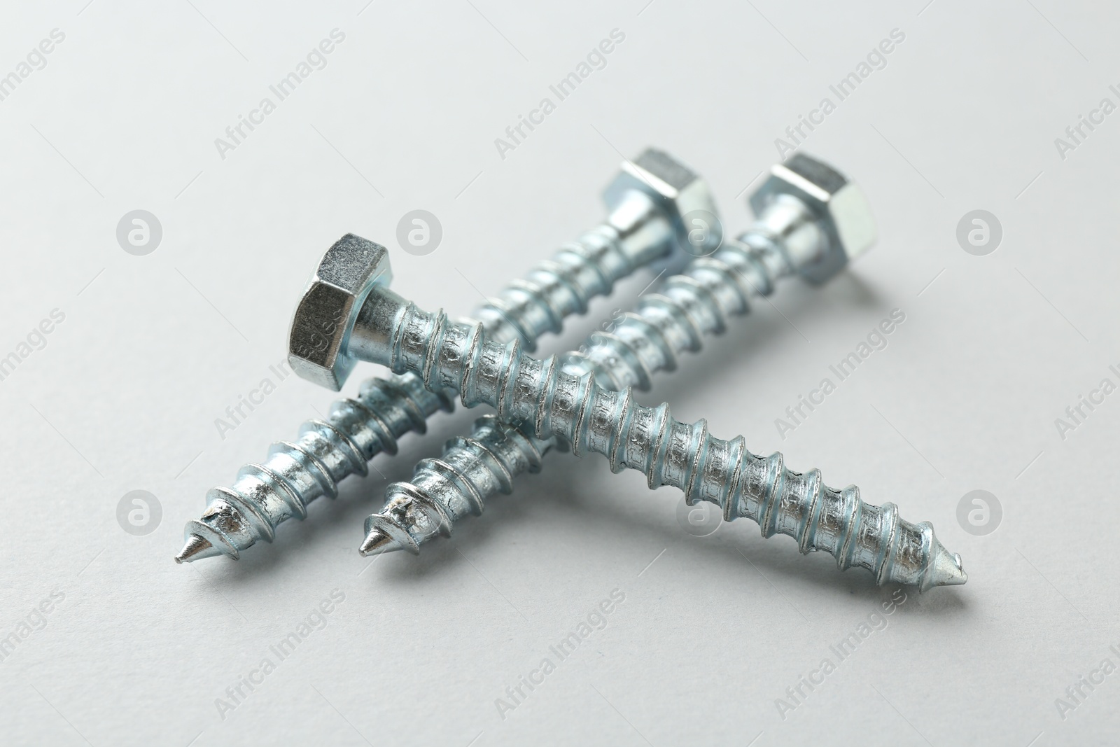 Photo of Three metal bolts on light grey background, closeup. Hardware tool