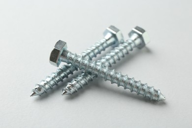 Photo of Three metal bolts on light grey background, closeup. Hardware tool