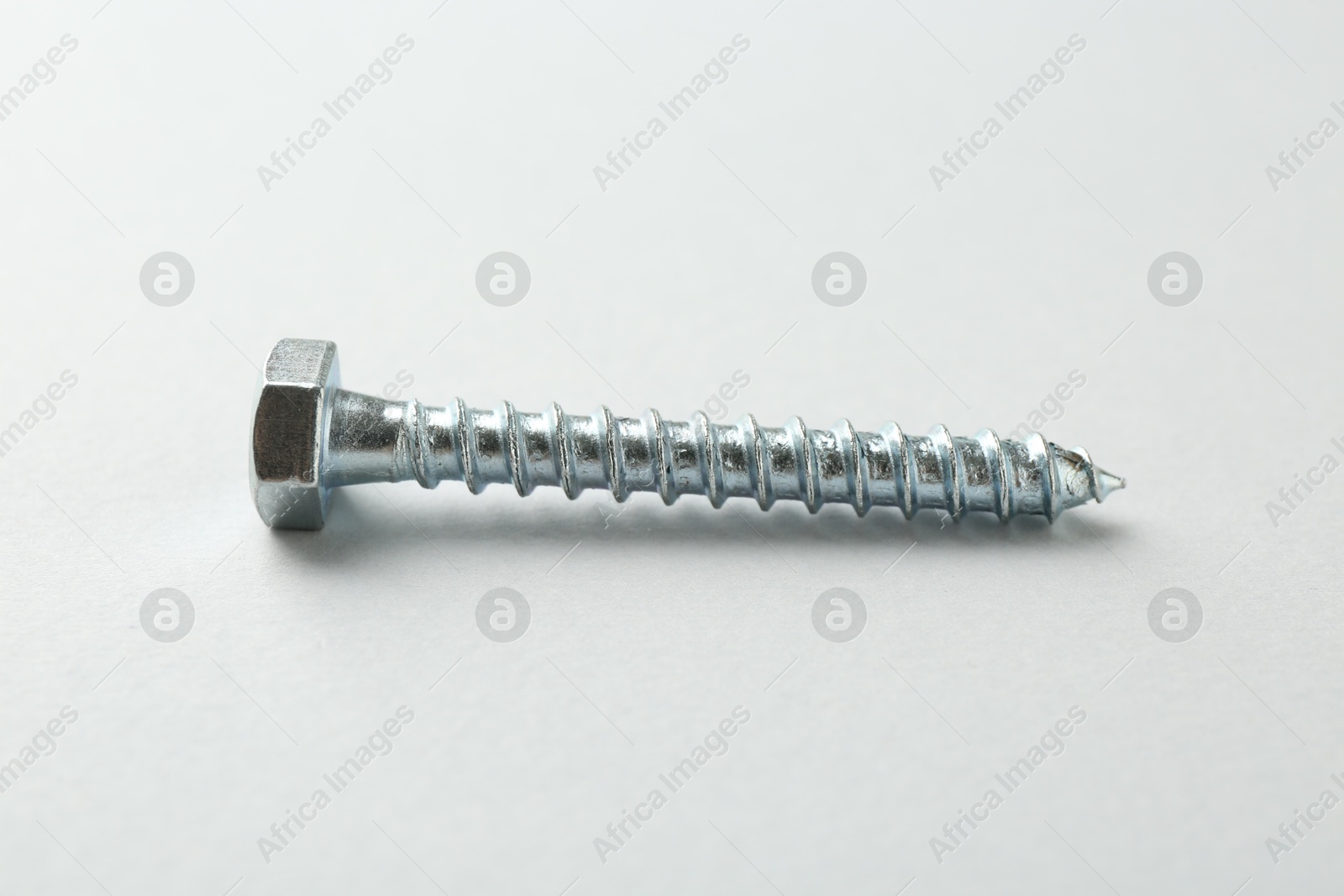Photo of One metal bolt on light grey background. Hardware tool