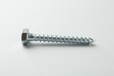 Photo of One metal bolt on light grey background. Hardware tool