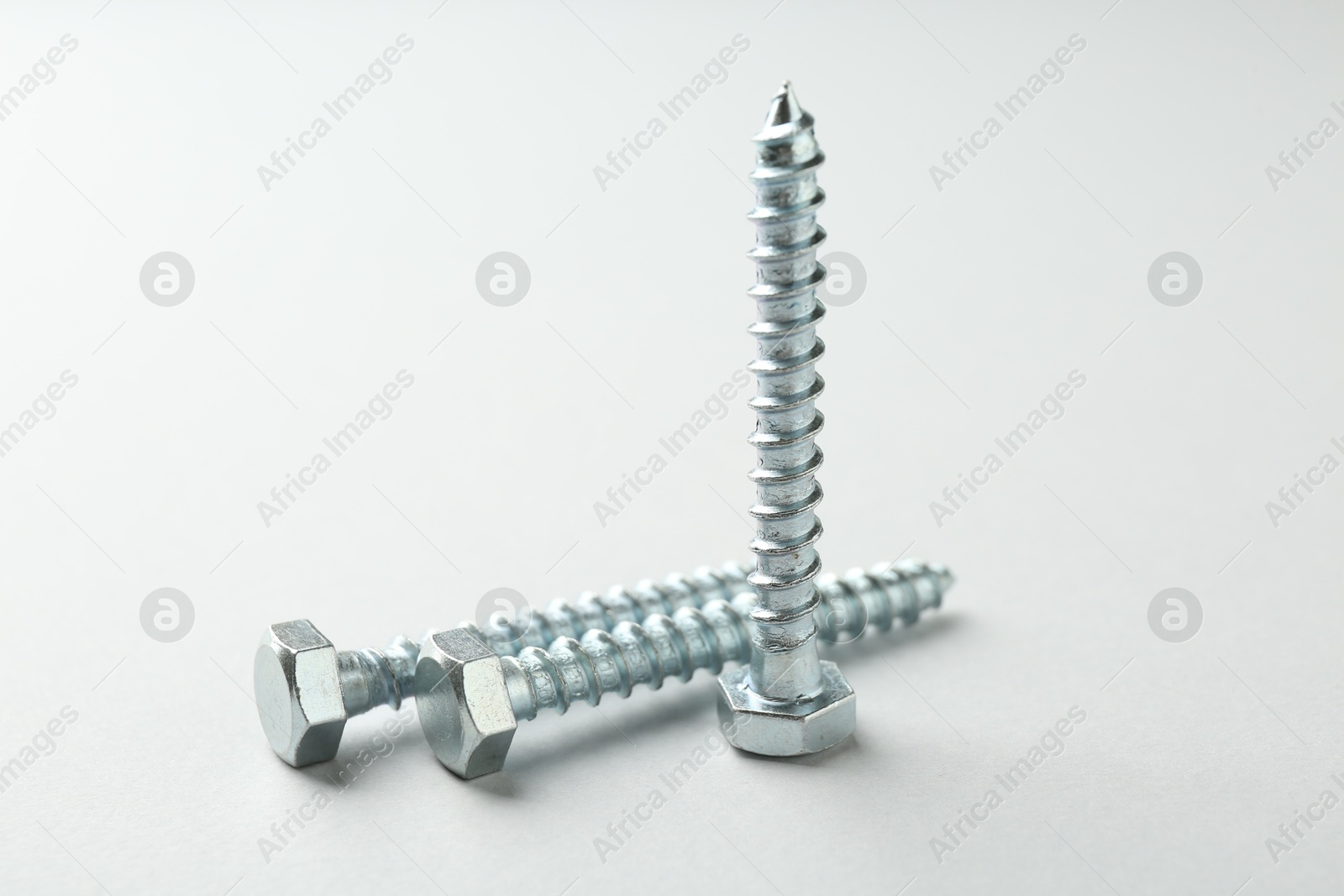 Three metal bolts on light grey background, closeup. Hardware tool Photo of Three metal bolts on light grey background, closeup. Hardware tool