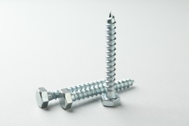 Photo of Three metal bolts on light grey background, closeup. Hardware tool