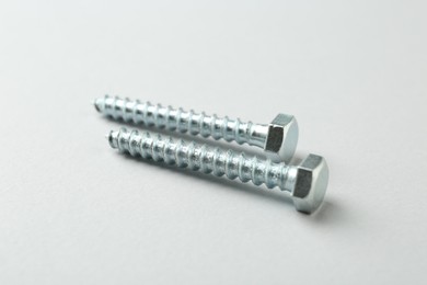 Photo of Two metal bolts on light grey background, closeup. Hardware tool