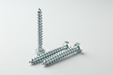 Photo of Three metal bolts on light grey background, closeup. Hardware tool