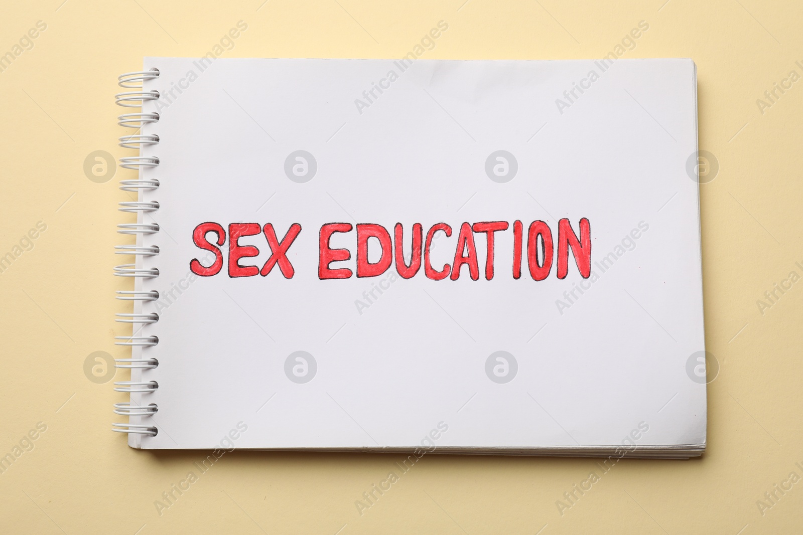 Photo of Notebook with words Sex Education on beige background, top view