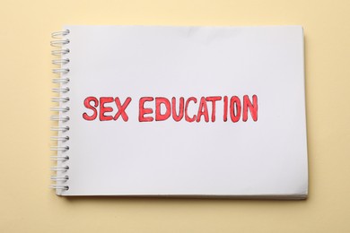 Photo of Notebook with words Sex Education on beige background, top view
