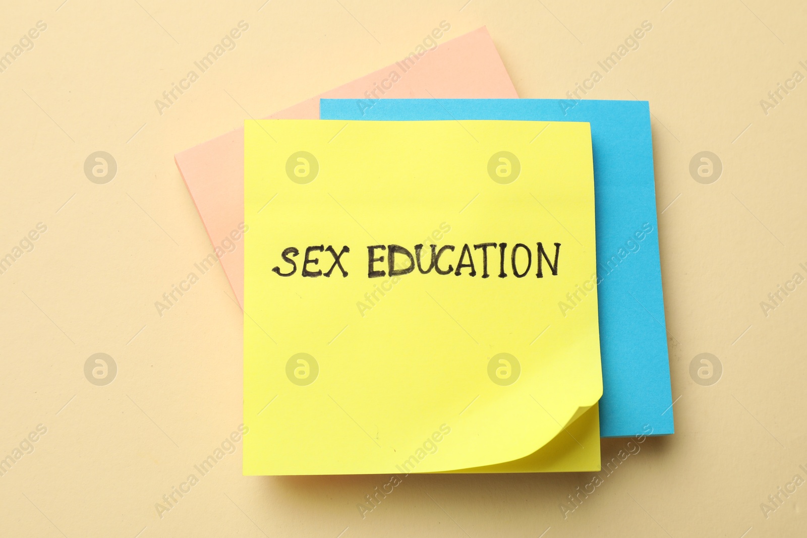 Photo of Sticky notes with words Sex Education on beige background, top view