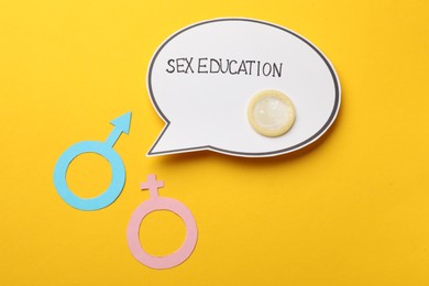 Photo of Paper speech bubble with words Sex Education, gender symbols and condom on yellow background, flat lay