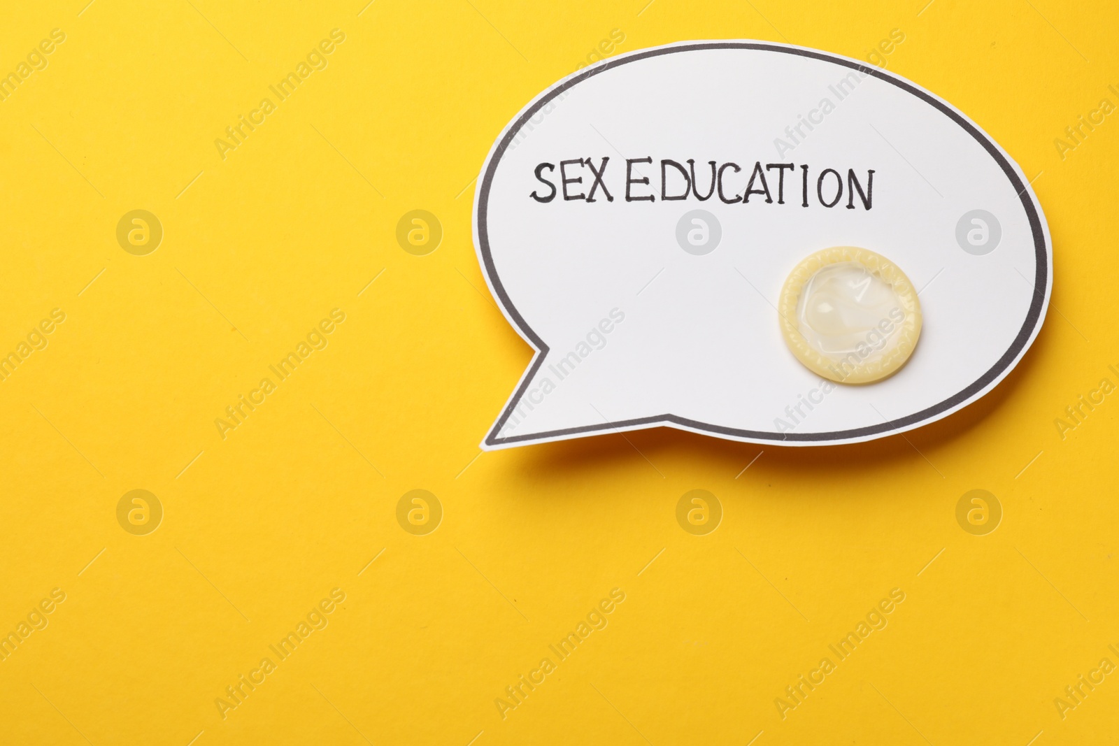 Photo of Paper speech bubble with words Sex Education and condom on yellow background, top view. Space for text