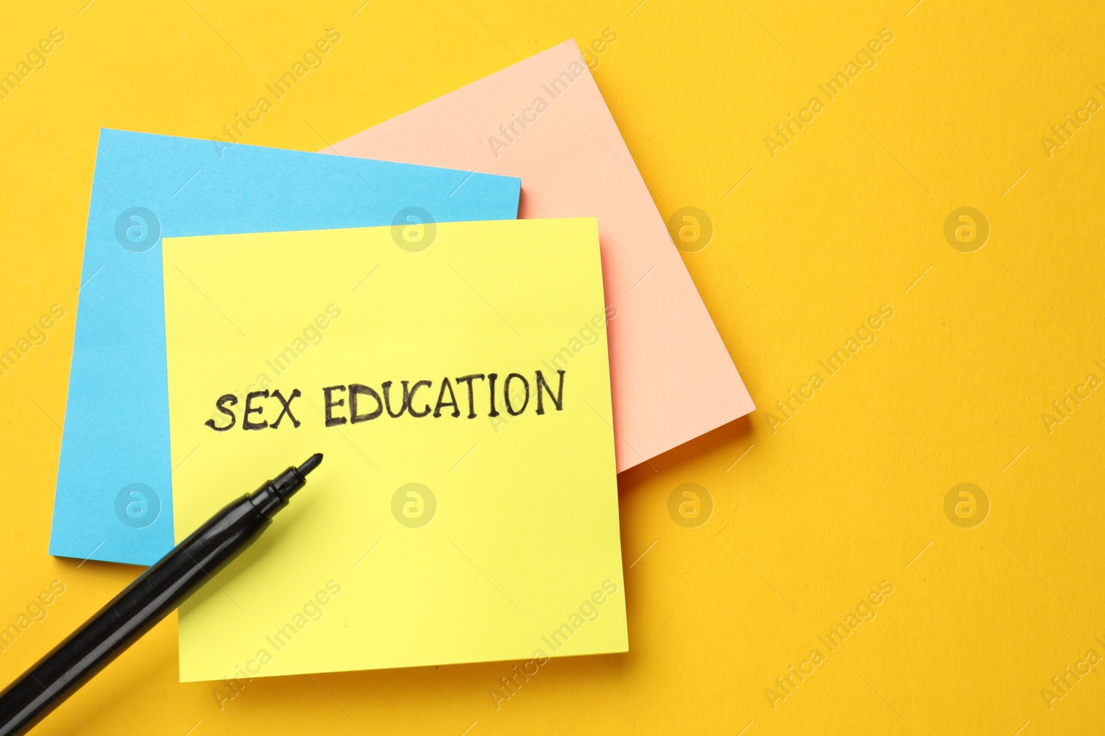 Photo of Sticky notes with words Sex Education and felt pen on yellow background, flat lay. Space for text